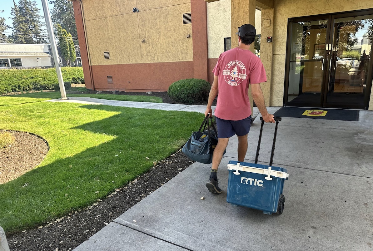 A man wheels a cooler into a hotel entrance.