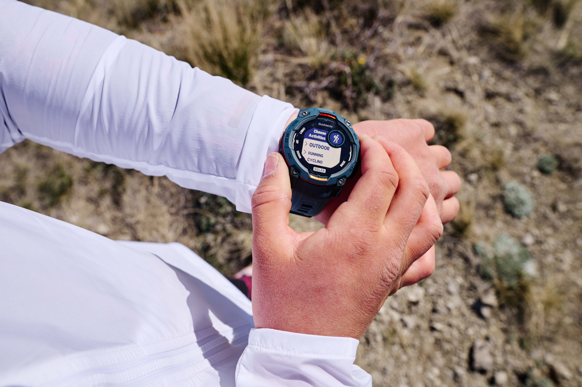 A close up of a GPS watch on a wrist and a hand adjusting settings
