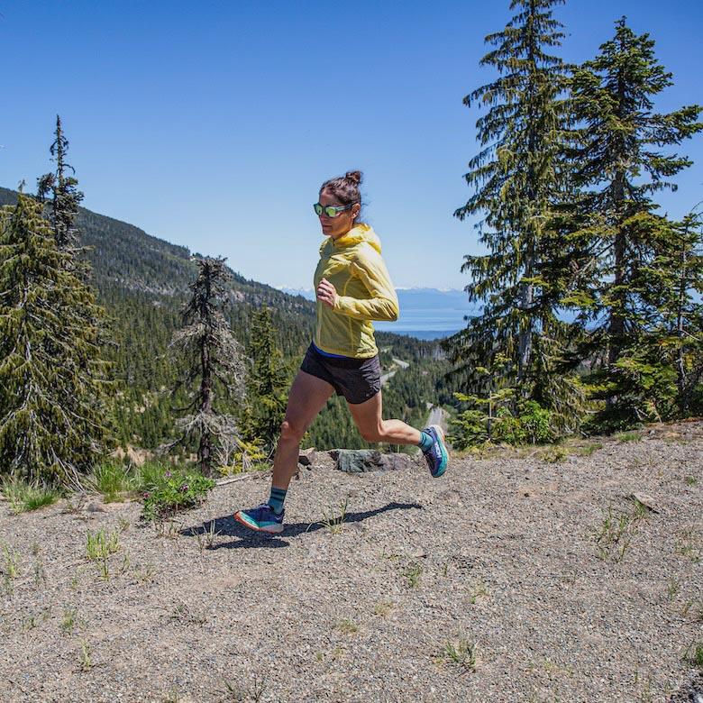 A woman runs on a dirt trail among the trees