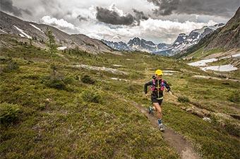 A woman running through mountainous alpine terrain